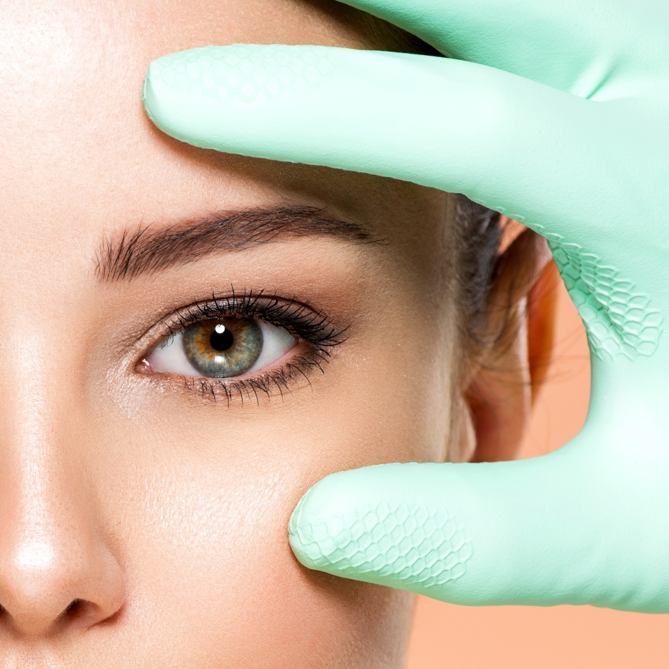 Face skin check before plastic surgery. Beautician touching young woman face. Doctor in medicine gloves checks a skin before plastic surgery. Beauty treatments. Colorful image